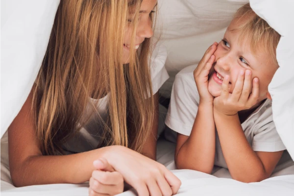 Dzieci śmiejące się ukrywające pod kołdrą